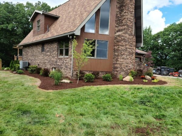 corner of cabin with mulch beds and plants