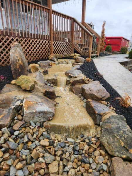 Water flowing through rocky landscape bed